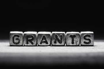 Wall Mural - Conceptual inscription grants on metal cubes on a black gray background close-up isolated