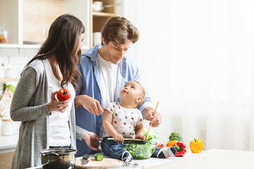 Wall Mural - Happy parents teaching baby son to prepare vegetable salad