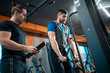© goami - young man has workout with personal trainer in modern gym