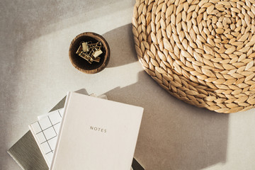 Wall Mural - Flatlay notebooks, clips in wooden bowl, straw stand on beige concrete background. Office desk workspace. Business, work blank template. Flat lay, top view.