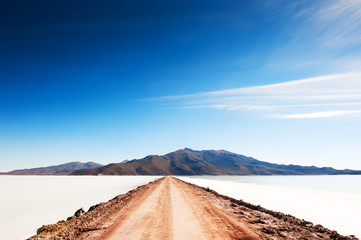 Wall Mural - Road to volcano on Salar de Uyuni salt flat in Bolivia. South America landscapes.