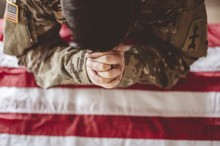 American Soldier Mourning And Praying With The American Flag In Front Of Him