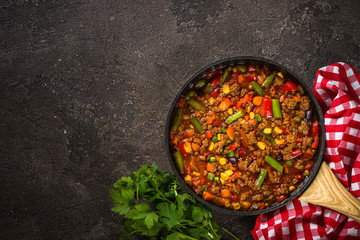 Wall Mural - Chili con carne in skillet on dark stone table.