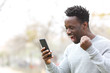 © PheelingsMedia - Excited black man celebrating mobile phone news