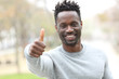 © PheelingsMedia - Happy black man gesturing thumbs up outdoors
