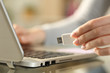 Woman holding usb flash drive next to laptop at home