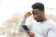 © PheelingsMedia - Surprised black man checking mobile phone news