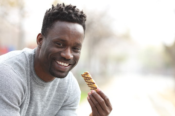 Happy black man holding granola bar looking at camera