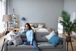 © BestForYou - Happy woman resting comfortably sitting on sofa in the living room at home.