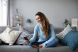 © BestForYou - Smiling young woman at home using modern smartphone.