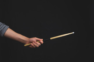 Hand holds drumstick in the dark. copy space