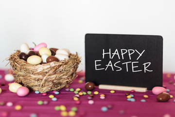 Wall Mural - Nest with easter almonds and blackboard with Happy Easter text