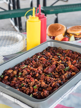 Baked Beans In Front Of Burgers On Outside Picnic Table Vertical