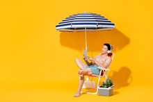 Portrait Of Young Shirtless Asian Man Sitting On Beach Chair Relaxing And Listening To Music In Isolated Summer Yellow Background