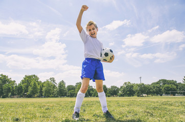 boy cheering with soccer ball on the field