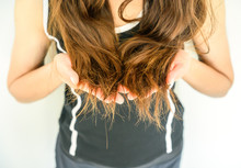 Cropped Shot View Of Woman Holding Her Damaged Split Ended Hair (Focus At Ends Hair). Hair Damage Is Risk For Further Damage And Breakage. It May Also Look Dull Or Frizzy And Be Difficult To Manage.