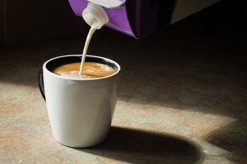 pouring cream into coffee cup