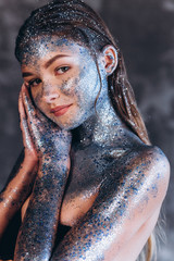 Close up portrait of young fashionable model with art make up with blue sparkles. Fashion, art, beauty concept