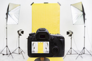 Camera in a photo studio with yellow backdrop and light equipment