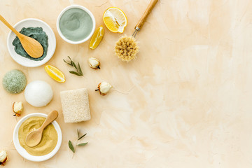 Face, body skin care homemade ingredients - cosmetic clay, brushes, homemade soap, scrub, herbs on a brown background. Top view