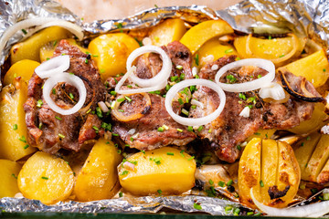 baked in foil pork neck, potatoes. close up