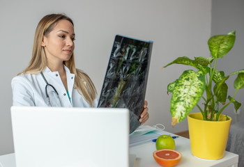 Young female doctor looking at the x-ray picture in her office