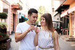 © Natalia - Romantic couple on date drinking coffee cappuccino in paper cups on street . Young blond woman, walking with brunette man with yummy coffee drink in summer in morning. Nutritious breakfast, snack.
