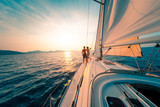 Young couple enjoys sailing in the tropical sea at sunset on their yacht.