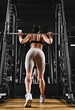 Beautiful girl trains legs, training in the gym, lifting weights, training on legs, squats, holding a barbell, powerlifting, fitness. Low key, copy space.