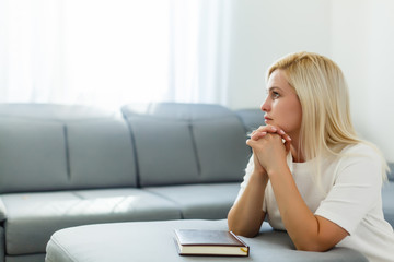 Girl praying. Side view of beautiful young blond hair woman praying at home