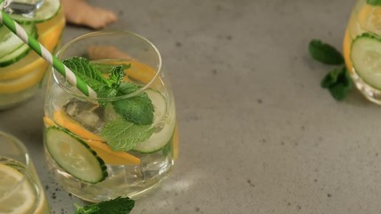 Wall Mural - Summer healthy lemonade, cocktails of citrus infused water or mojitos, with lime lemon orange, ice and mint, diet detox beverages, in glasses on gray background. Camera slide left.