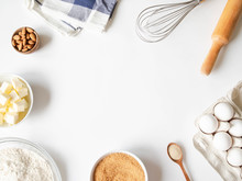 Frame Of Various Baking Ingredients - Flour, Eggs, Sugar, Butter, Dry Yeast, Nuts And Kitchen Utensils On White Background. Top View.