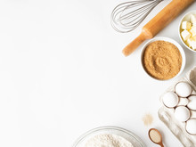 Frame Of Various Baking Ingredients - Flour, Eggs, Sugar, Butter, Dry Yeast, And Kitchen Utensils On White Background. Top View. Copy Space