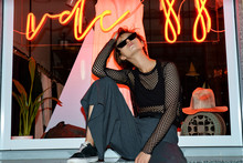 Pretty Young Girl Hipster Teen Model Advertise Trendy Dark Clothing Sunglasses Sit Pose Over Big Shop Window Led Lighting Showcase Background High Fashion Urban Lifestyle Night Life Concept Copyspace.