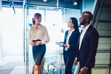 Wall Mural - Multiethnic business partners communicating while stepping after female secretary to office