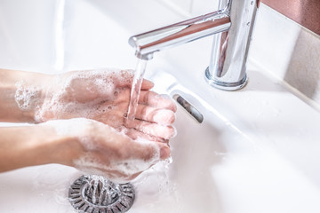 Washing hands with water and liquid soap in the bathroom. Hygiene anti-virus concept