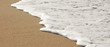 Bannière d'une douce vague blanche pleine d'écume sur le sable d'une plage de sable fin