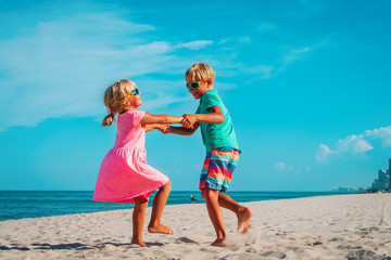 Wall Mural - happy boy and girl dance at beach, kids enjoy vacation