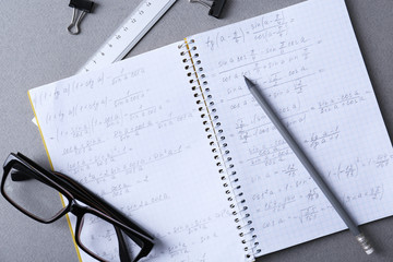 Notebook, pencil and glasses on light grey table, flat lay. Doing homework