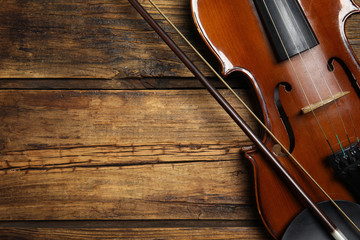 Classic violin and bow on wooden background, top view. Space for text