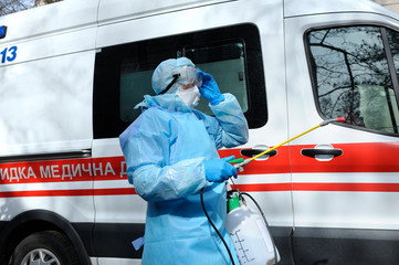 Paramedics disinfecting the ambulance car with the motorized backpack sprayer