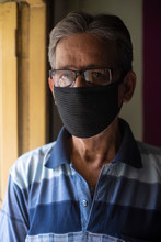 Portrait Of An Indian Old Man Wearing Corona Preventive Mask In Isolation In Front Of A Window. Indian Lifestyle And Disease.