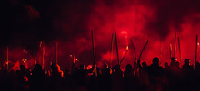 A Medieval Troop On The Battlefield At Night. Silhouettes Of The Fighting Medieval Soldiers On The Red Foggy Background. Rebels During A Riot With Torches At Night.