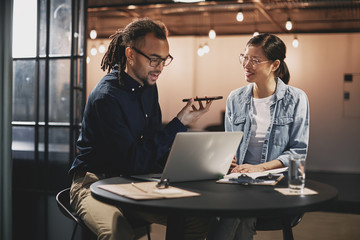 Smiling young businesspeople talking with a client over the phon