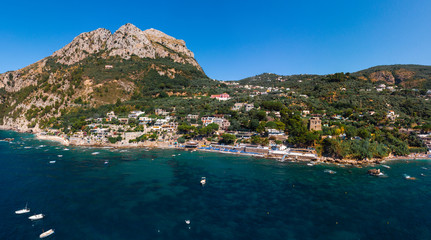 Aerial view of coastline of the village of Nerano. Private and wild beaches of Italy. Turquoise, blue surface of the water. Vacation and travel concept. Boats on raid in bay. Copy space. Summer day