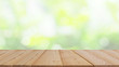 brown wood plank table top on blur and bokeh abstract green tree in the garden using for banner design or natural montage display product background concept.