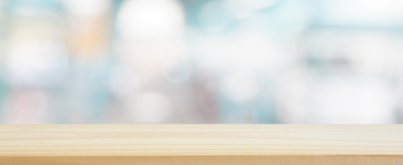 wood plank table top on blur and bokeh abstract in the department store with blue color tone using for design shopping background and banner montage display product layout