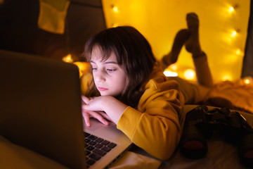Wall Mural - little 11 year old girl using laptop under her home-made tent inside the living room.