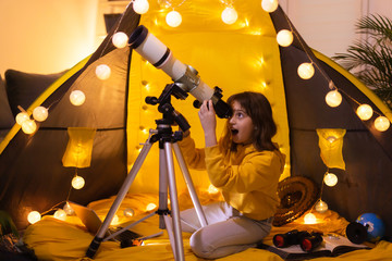 Wall Mural - small girl using telescope at home living room in a tent.