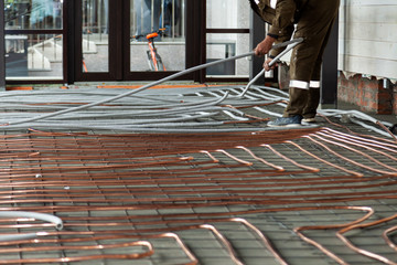 Wall Mural - Plumber laying copper pipes on floor with warm heating